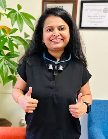 The image shows a woman giving a thumbs-up gesture while standing in an office setting.