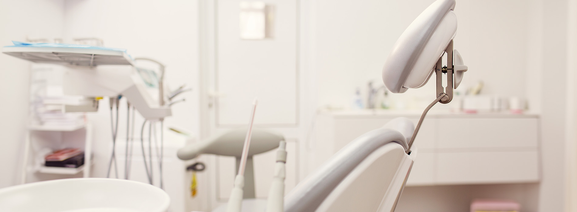 The image shows a modern dental clinic interior with various pieces of equipment, including a dental chair and an X-ray machine.