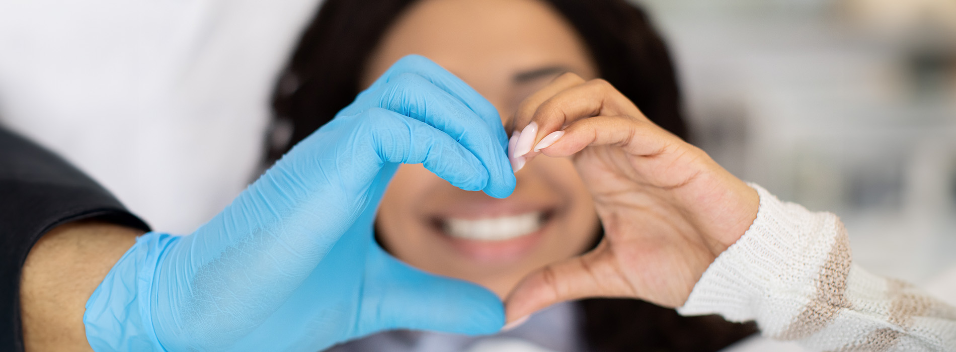 The image shows a group of people, possibly professionals given their attire and the setting that appears to be an office or professional environment. They are gathered around a table with a laptop on it, engaged in what seems to be a discussion or meeting.