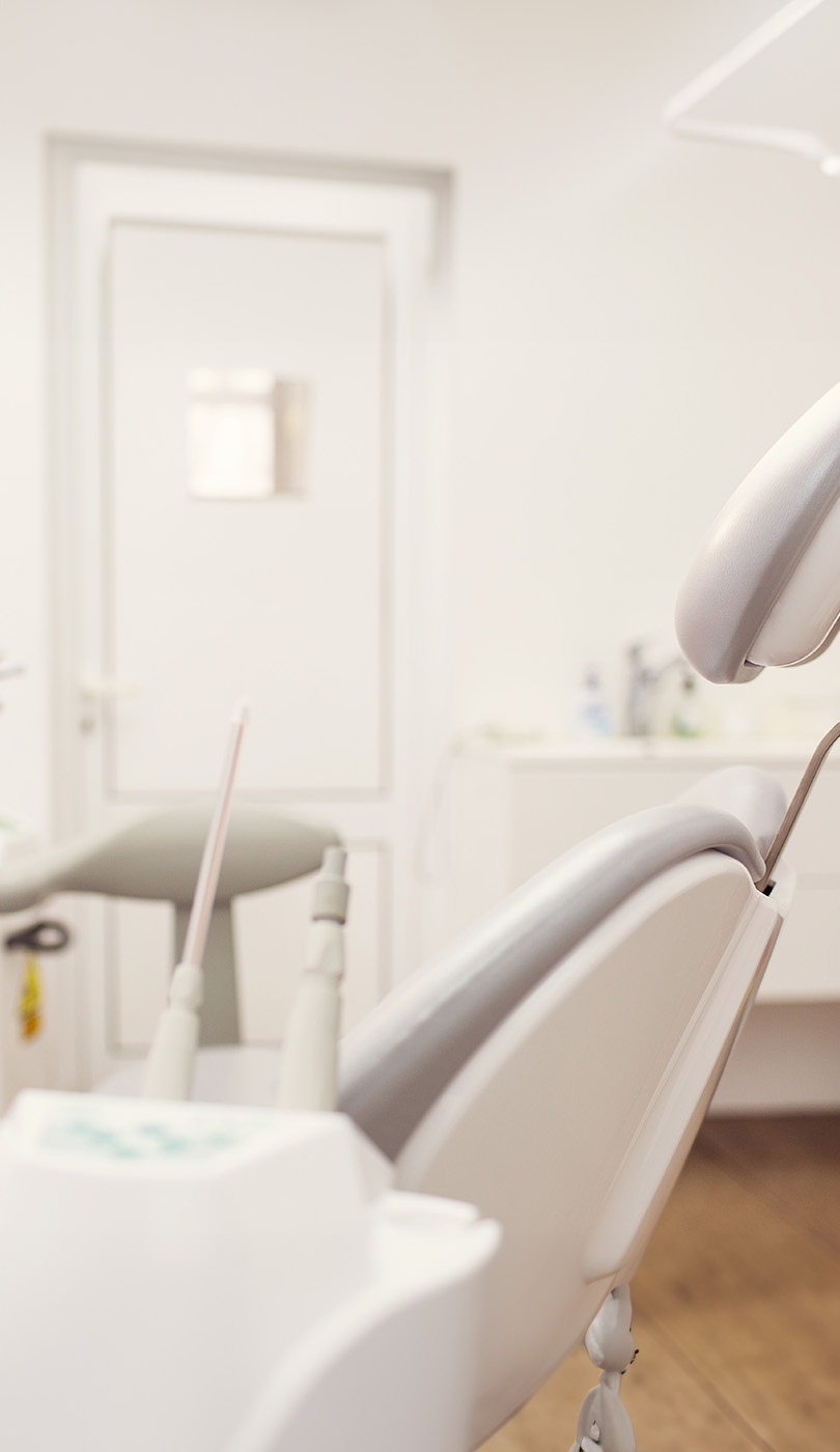 The image shows a modern dental or medical office interior with a dental chair, equipment, and a clean, professional environment.