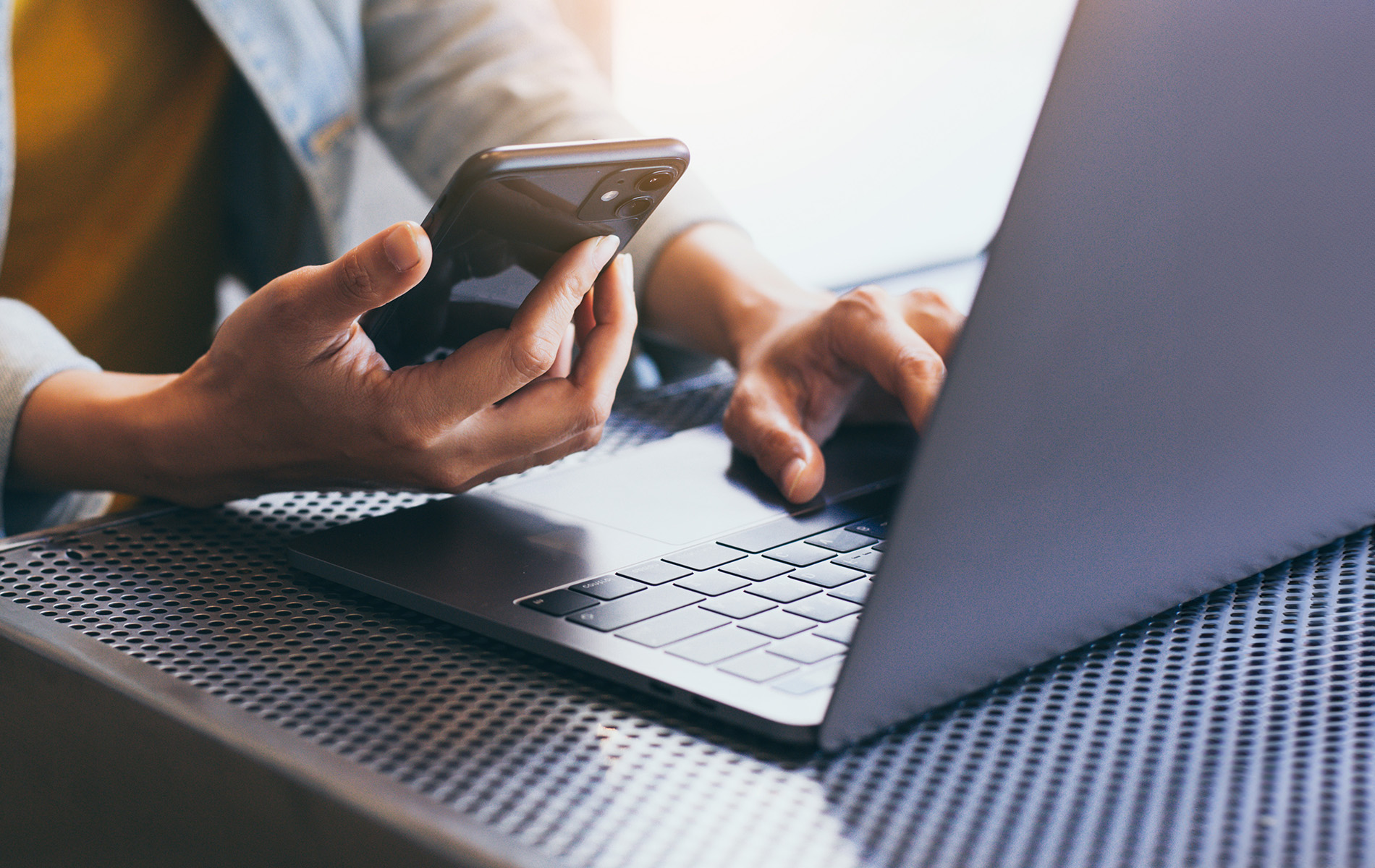 A person s hands texting on a laptop with a blurred background.