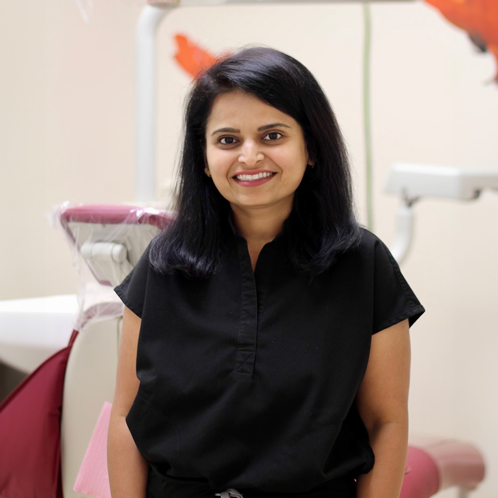 A woman standing in front of dental equipment, smiling at the camera.