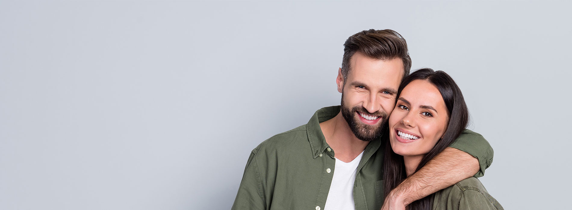 A man and a woman are standing closely together, smiling at the camera.