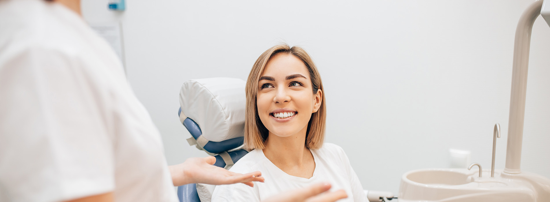 A woman in a dental chair receiving care from a smiling dentist.