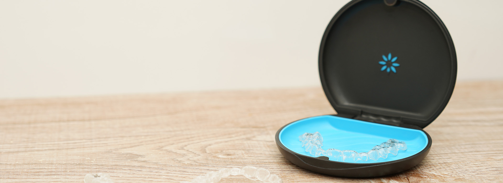 The image shows a smartphone charging station with a blue circular base and a black charging dock, set against a beige background.