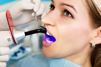 A woman receiving dental treatment, with a dentist using a device to scan her teeth.