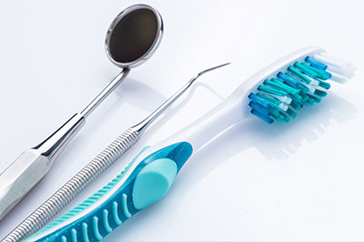 Dental tools including a toothbrush, dental mirror, and dental pick on a white background.