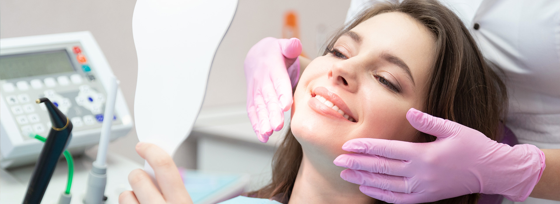 The image depicts a woman in a dental chair receiving dental care, with a dentist s hand visible holding a mirror to the patient s face.