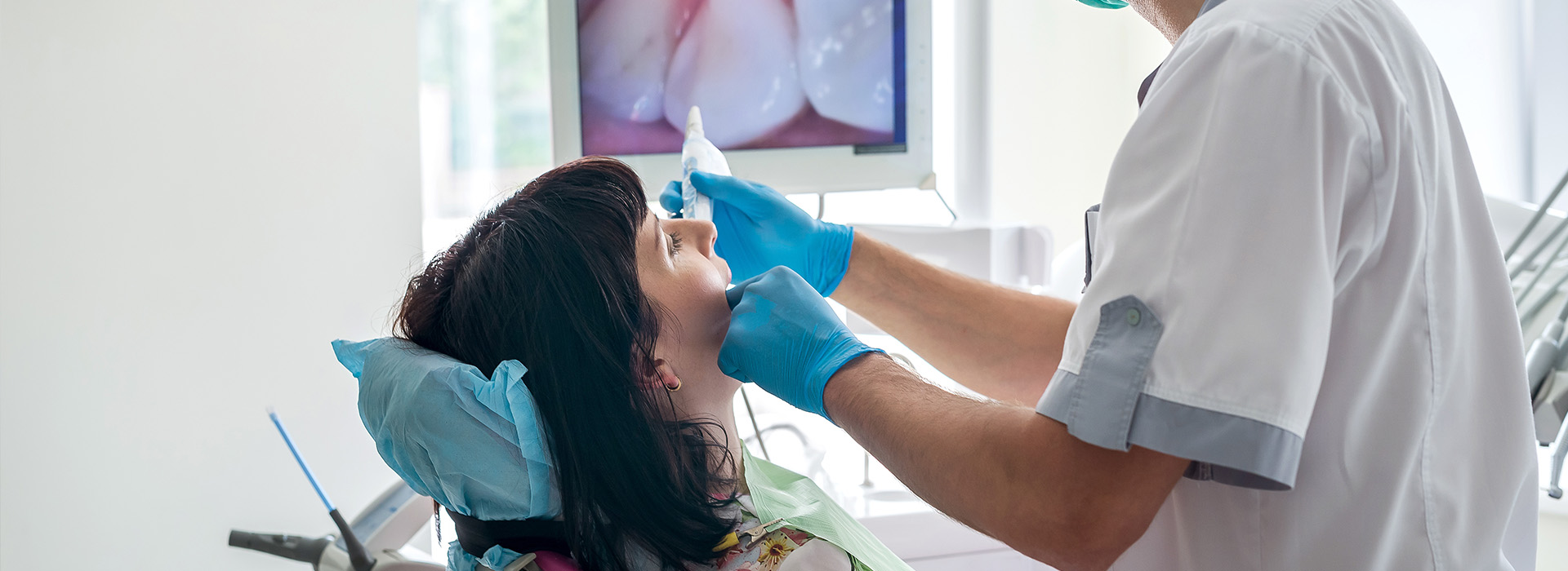 A dental hygienist is cleaning a patient s teeth using a small handheld brush and water spray.