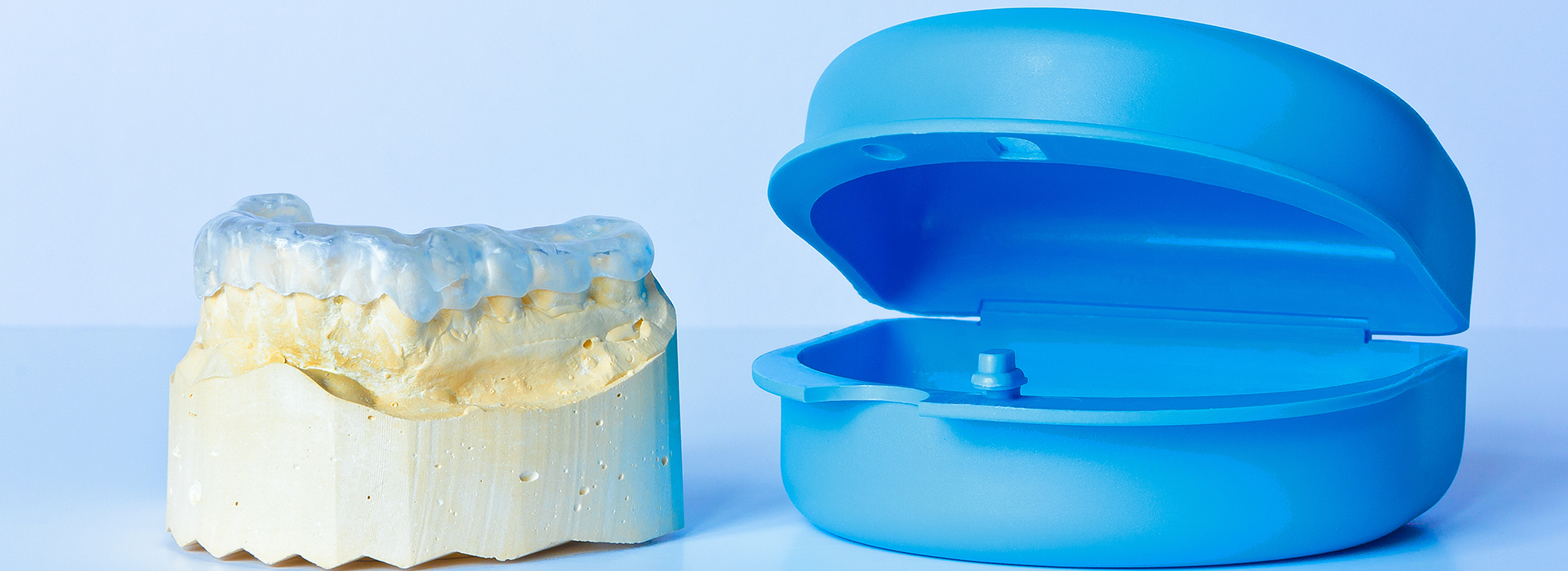 The image features a blue dental implant on the right and a yellow dental implant on the left, both set against a white background.