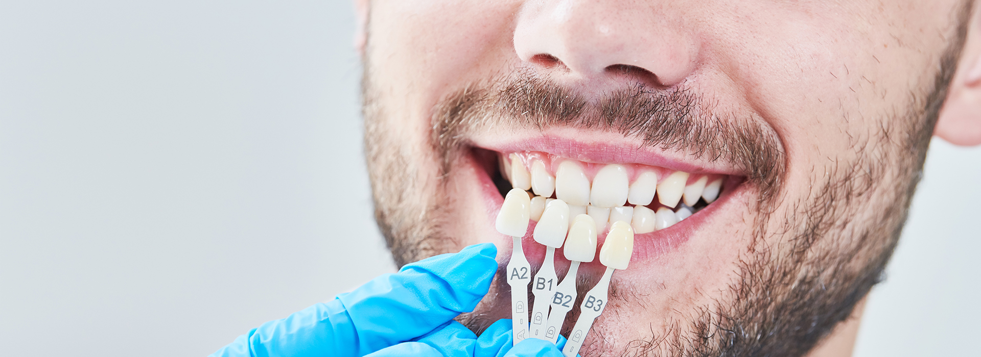 Man in lab coat smiling with dental implant, close-up view of mouth and teeth.