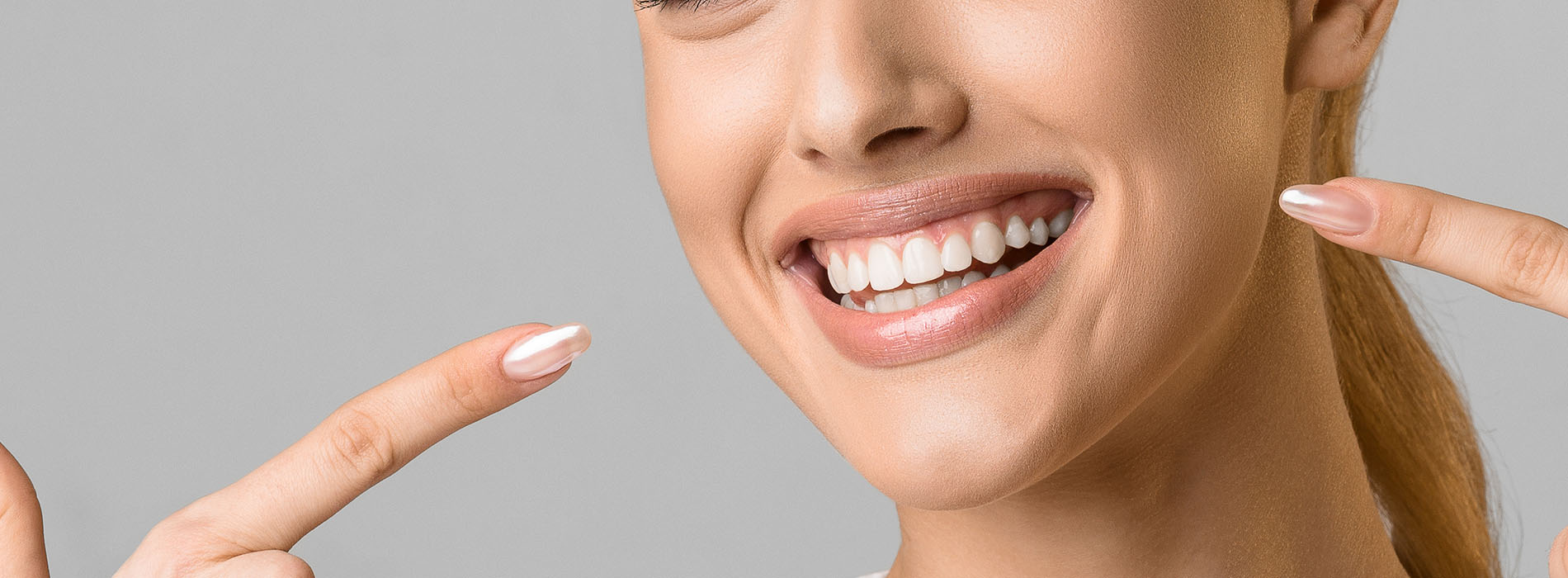 A smiling woman with a manicure holding up a peace sign.