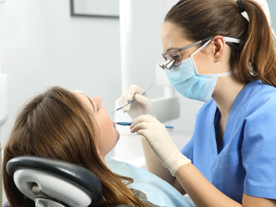 Dental hygienist performing oral care on patient in dental office setting.