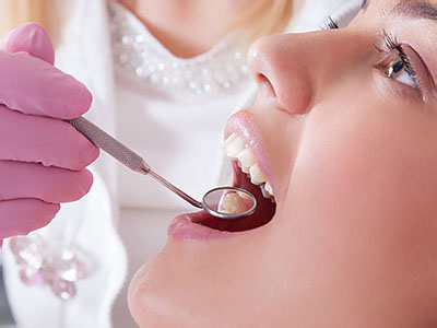 An adult woman receiving dental care, with a dentist using a dental drill on her teeth.