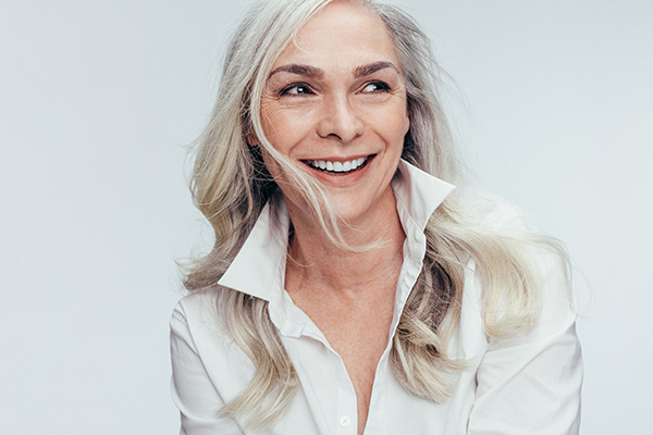 A woman with short hair and a slight smile, wearing a white shirt, against a plain background.