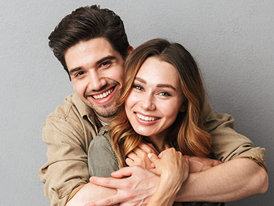 A man and a woman are smiling and hugging each other in a close embrace.