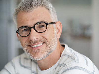 A man with glasses, a beard, and mustache is smiling at the camera.