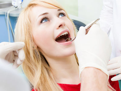 A woman sitting in a dental chair, receiving dental care with a smile on her face.