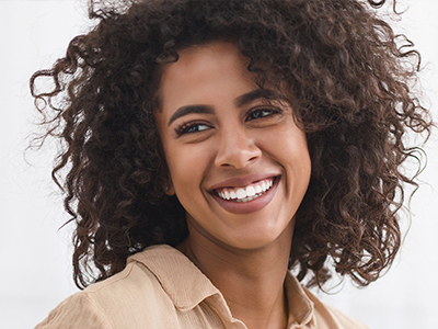 Smiling woman with curly hair and a bright smile, against a white background.